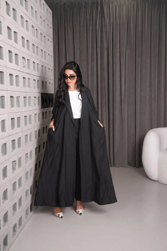 Woman wearing black free-size linen blazer over white top and black pants in modern room
