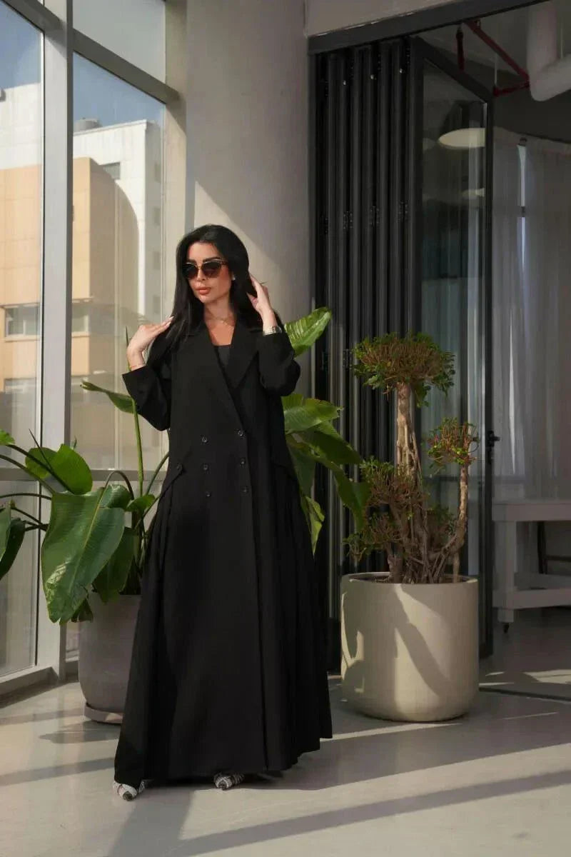 woman wearing a stylish black crepe blazer with double-breasted front and three buttons on each side in a modern indoor setting