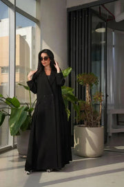 woman wearing a stylish black crepe blazer with double-breasted front and three buttons on each side in a modern indoor setting