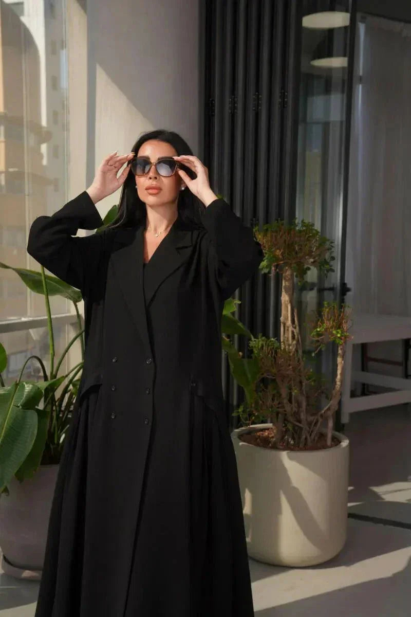 woman wearing a stylish black crepe blazer with double-breasted front and three buttons on each side in a modern indoor setting