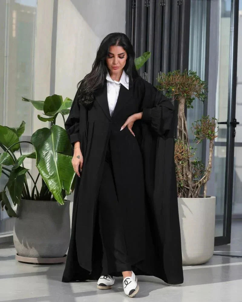 Woman wearing a free-size black blazer with wide pleated details made of soft crepe fabric.