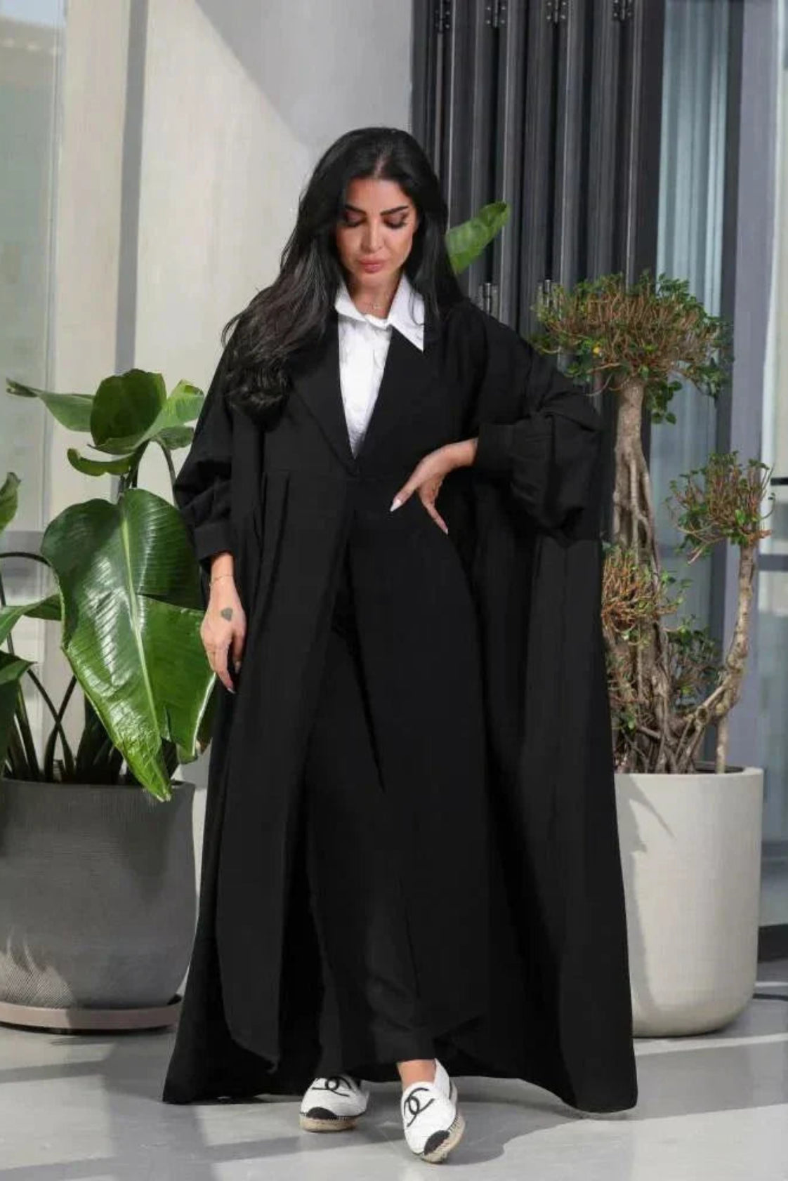 Woman wearing a free-size black blazer with wide pleated details made of soft crepe fabric.