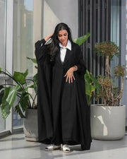 Woman wearing a free-size black blazer with wide pleated details made of soft crepe fabric.