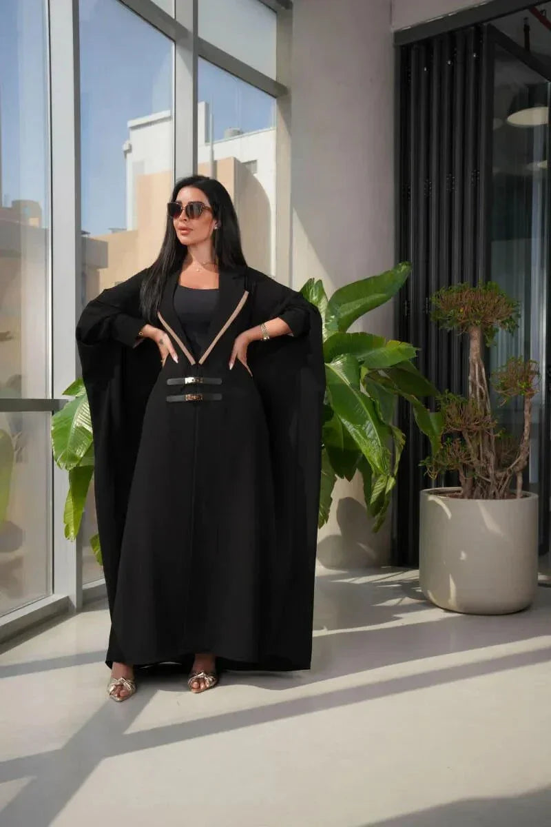 Black crepe abaya with two small leather belts worn by woman in modern indoor setting