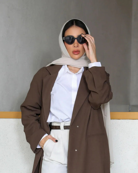 brown blazer-style abaya with structured lapel collar and front button closure worn over white shirt and beige pants