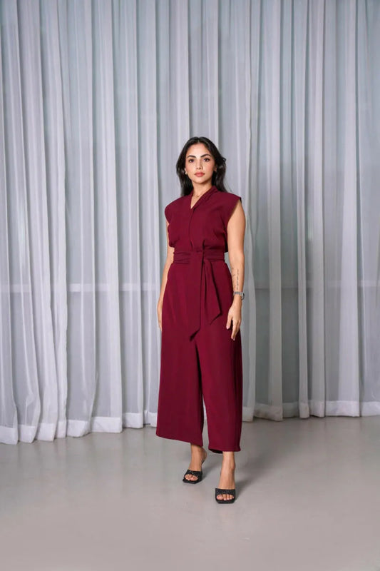Woman wearing sleeveless burgundy V-neck jumpsuit with wide legs and detachable belt.