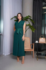 Woman wearing sleeveless emerald green tailored jumpsuit with V-neckline, wide-leg pants, and matching belt.