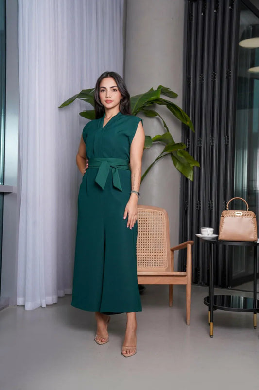 Woman wearing sleeveless emerald green tailored jumpsuit with V-neckline, wide-leg pants, and matching waist belt.