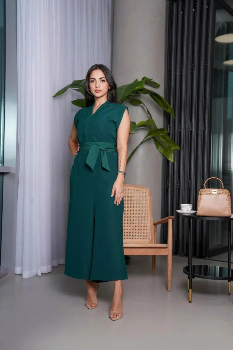 Woman wearing sleeveless emerald green tailored jumpsuit with V-neckline, wide-leg pants, and matching belt.