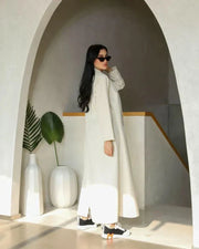 Cream blazer-style abaya with double-breasted black buttons and side pockets, tailored in structured crepe fabric for a modern classic look.