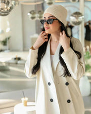 Cream blazer-style abaya with double-breasted black buttons and side pockets, tailored in structured crepe fabric for a modern classic look.