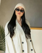 Cream blazer-style abaya with double-breasted black buttons and side pockets, tailored in structured crepe fabric for a modern classic look.