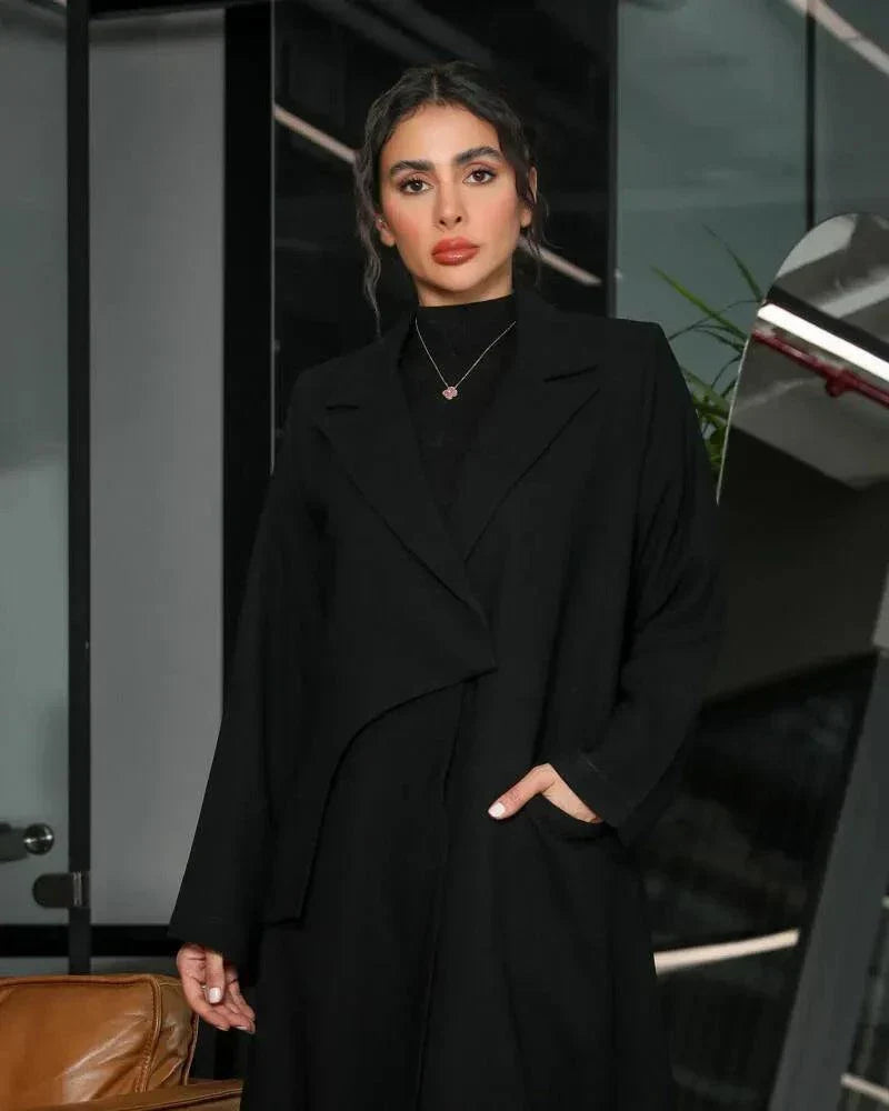 Woman wearing a sleek black Contour blazer-style abaya with clean lapel collar and overlapping front panel, styled for elegant workwear - Contor blazer-style abaya