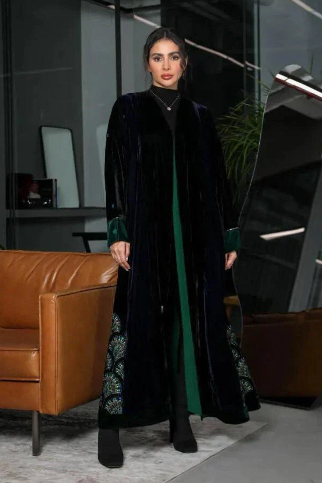 woman wearing black and navy velvet abaya with emerald green chiffon lining and green velvet cuffs standing indoors