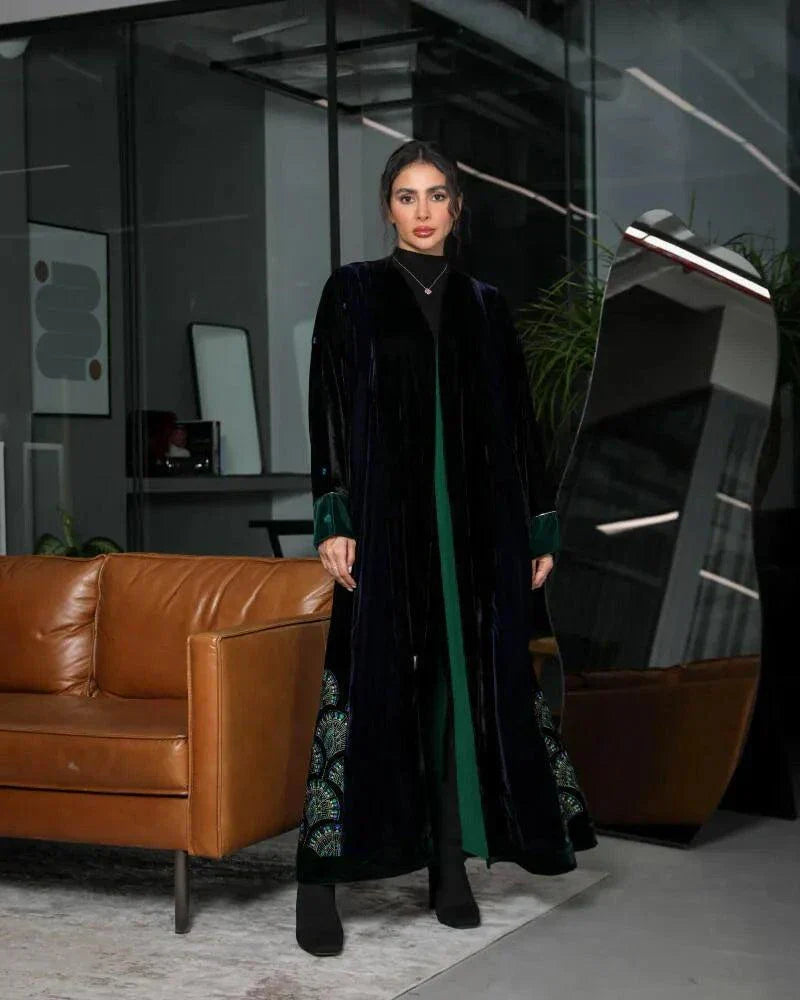 woman wearing black and navy velvet abaya with emerald green chiffon lining and green velvet cuffs standing indoors