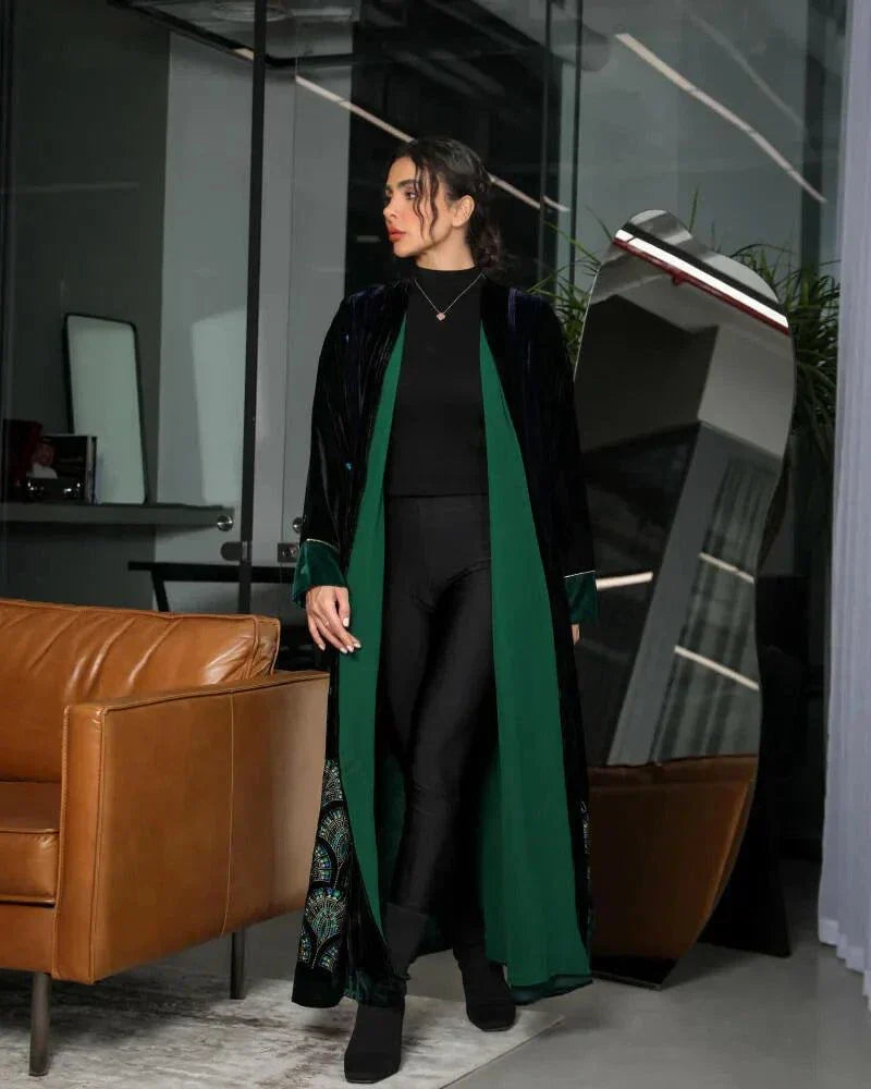 woman wearing black and navy velvet abaya with emerald green chiffon lining and green velvet cuffs standing indoors
