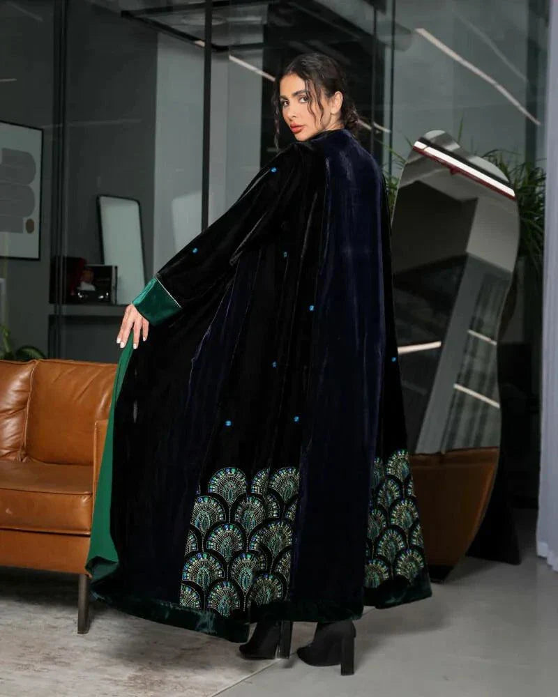 woman wearing black and navy velvet abaya with emerald green chiffon lining and green velvet cuffs standing indoors