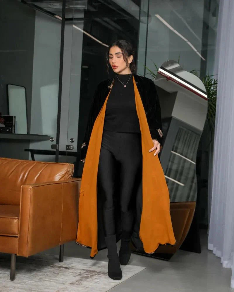 luxurious black velvet abaya with gold and beige geometric embroidery and bold orange chiffon lining in a relaxed silhouette