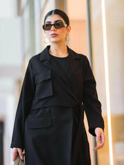 Black blazer-style abaya with structured crepe fabric, sharp lapel collar, oversized flap pockets, and wrap closure.