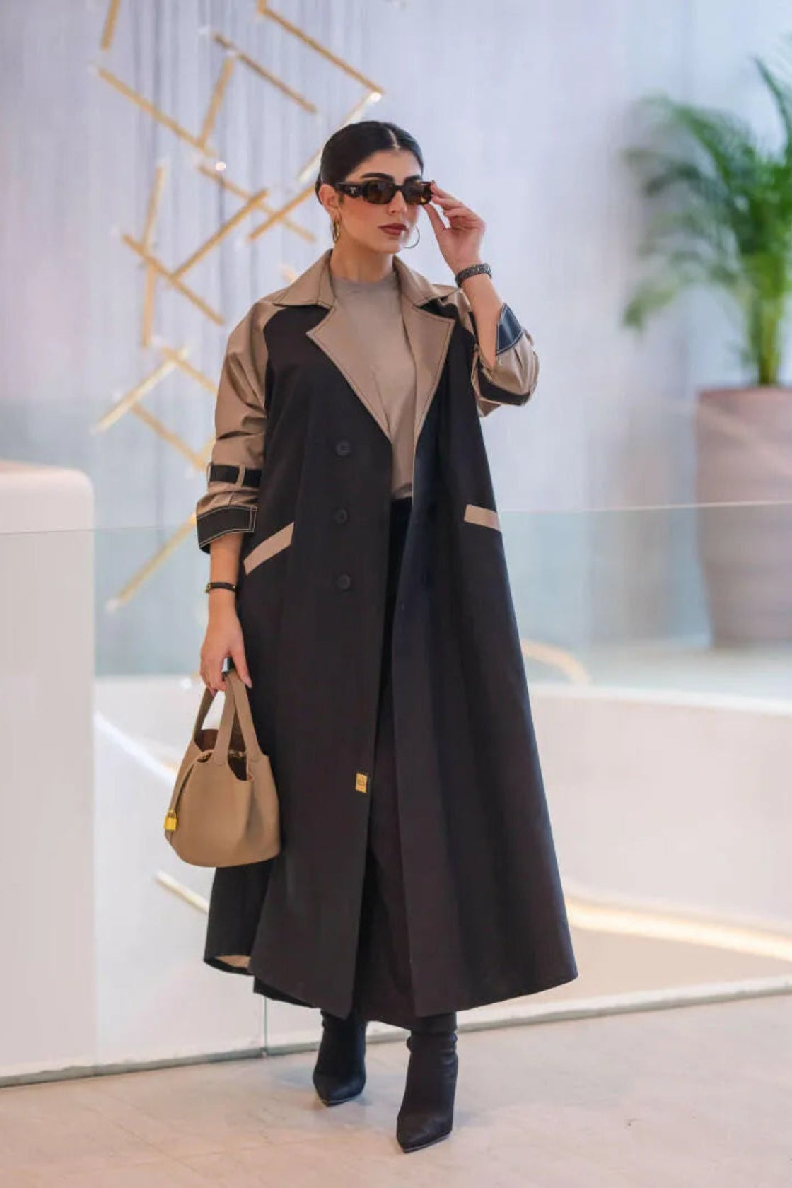 woman wearing a two-tone long structured blazer in black and olive-beige with sunglasses and a beige handbag