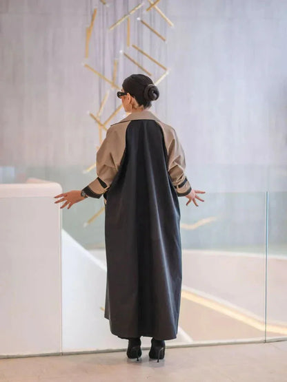 woman wearing long structured two-tone black and olive beige blazer abaya with double-breasted front and contrast sleeves carrying beige handbag - long structured blazer