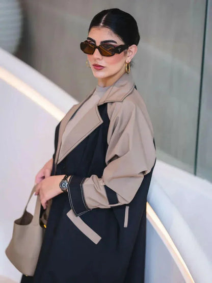 woman wearing long structured two-tone black and olive beige blazer abaya with double-breasted front and contrast sleeves carrying beige handbag - long structured blazer