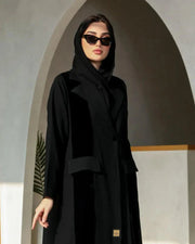 Woman wearing a black blazer-style abaya with structured lapels and single-button closure in a flowy crepe fabric.