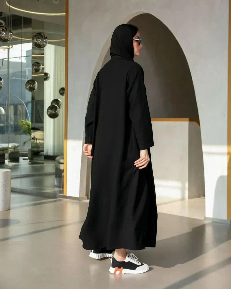 Woman wearing a black blazer-style abaya with structured lapels and single-button closure in a flowy crepe fabric.