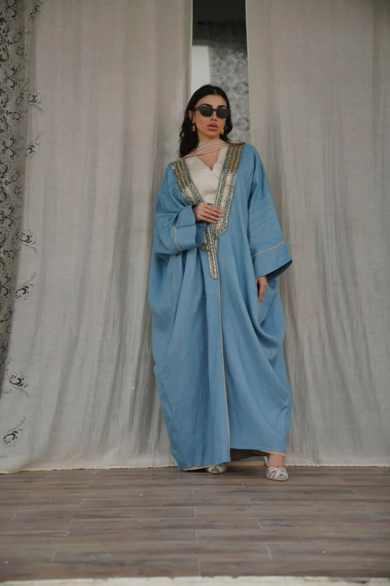 soft blue linen bisht with golden embroidery on neckline and cuffs, loose fit with wide sleeves, lightweight and elegant for warm weather and special occasions