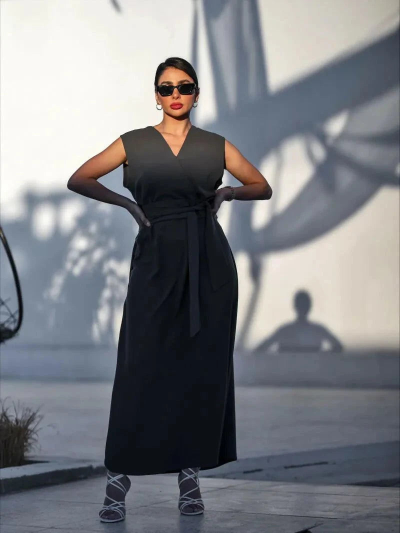 Woman wearing sleeveless dark gray crepe dress with V-neckline and waist tie outdoors