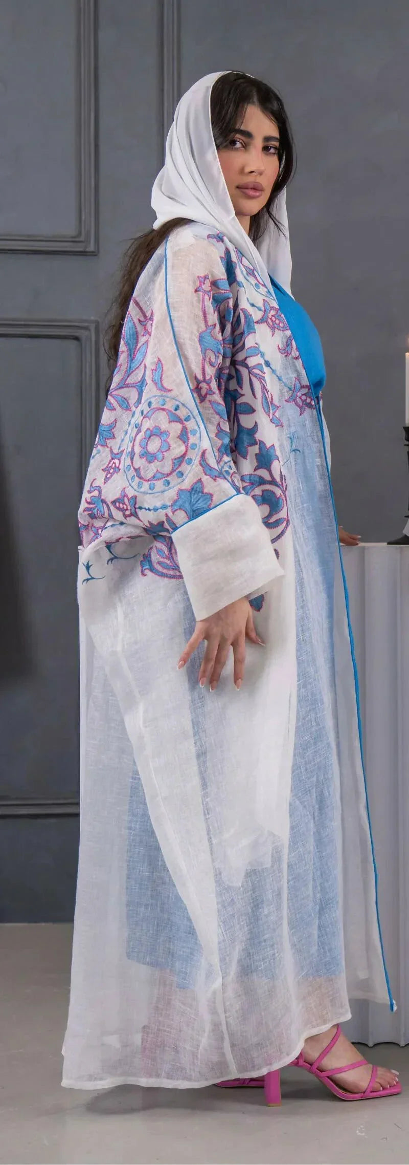 white bisht with blue and pink floral embroidery, lightweight linen fabric, loose fit with hood, styled over blue dress