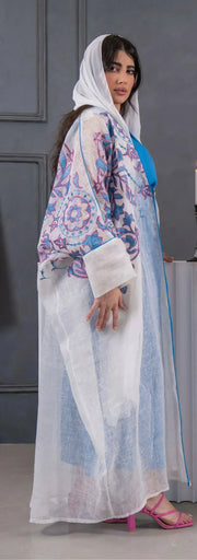 white bisht with blue and pink floral embroidery, lightweight linen fabric, loose fit with hood, styled over blue dress