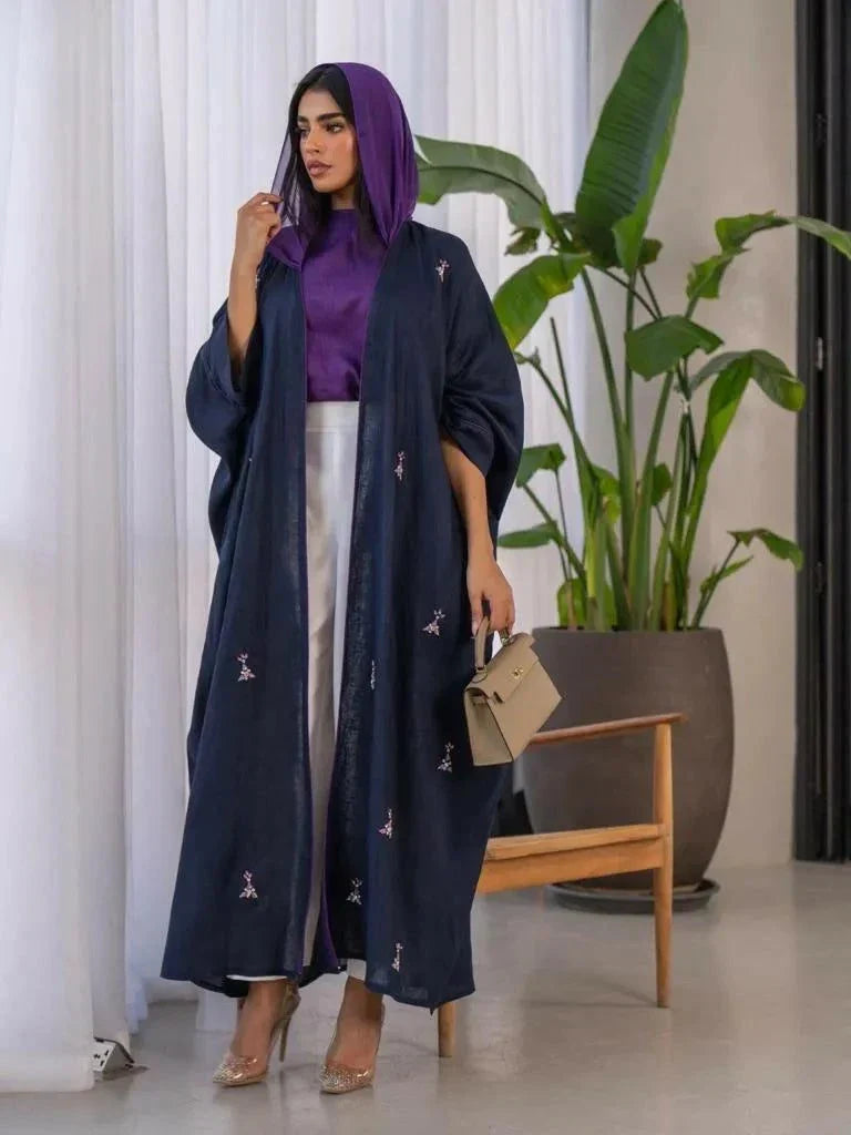 Woman wearing a navy blue Mystic bisht with subtle purple lines and hand-stitched accents paired with a purple blouse and white pants.