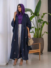 Woman wearing a navy blue Mystic bisht with subtle purple lines and hand-stitched accents paired with a purple blouse and white pants.