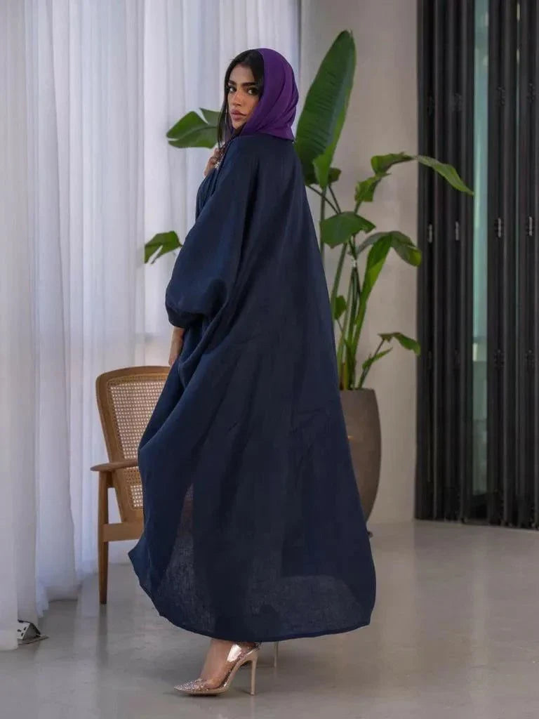 Mystic navy blue linen bisht with purple lines and hand-stitched accents styled with a purple blouse and white pants.