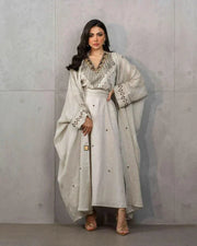 Woman wearing a beige three-piece linen set with sleeveless embroidered top, high-waisted skirt, and matching shawl with stitched accents.