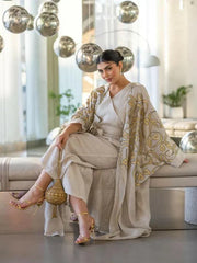 beige linen bisht with gold embroidery and wide sleeves worn by woman in modern indoor setting