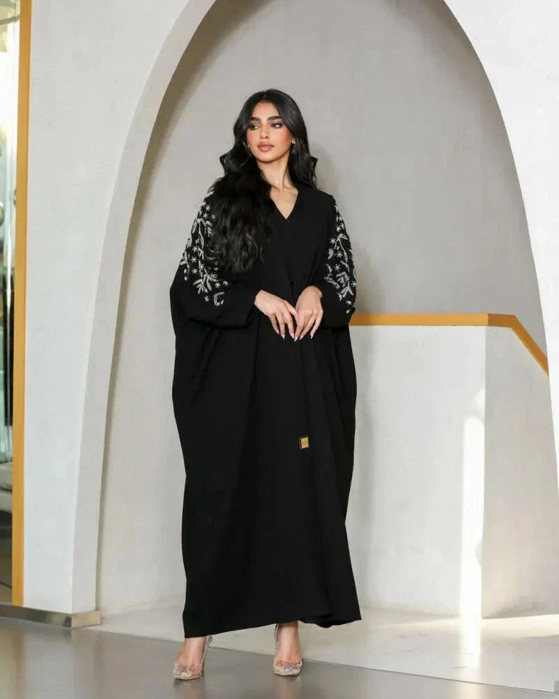 Elegant black abaya with silver nature-inspired embroidery on sleeves and V-neckline, made from smooth crepe fabric