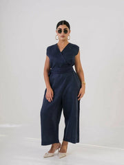 Woman wearing navy linen jumpsuit with V-neckline, fabric belt, and wide-leg pants, styled with sunglasses and heels