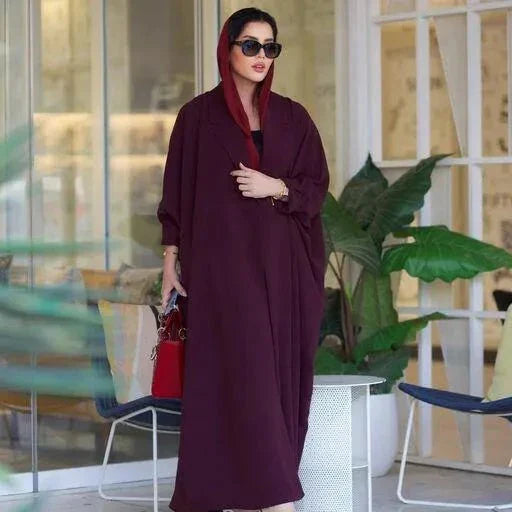 Woman wearing a stylish burgundy blazer abaya made from premium crepe fabric, accessorized with sunglasses and a red handbag.