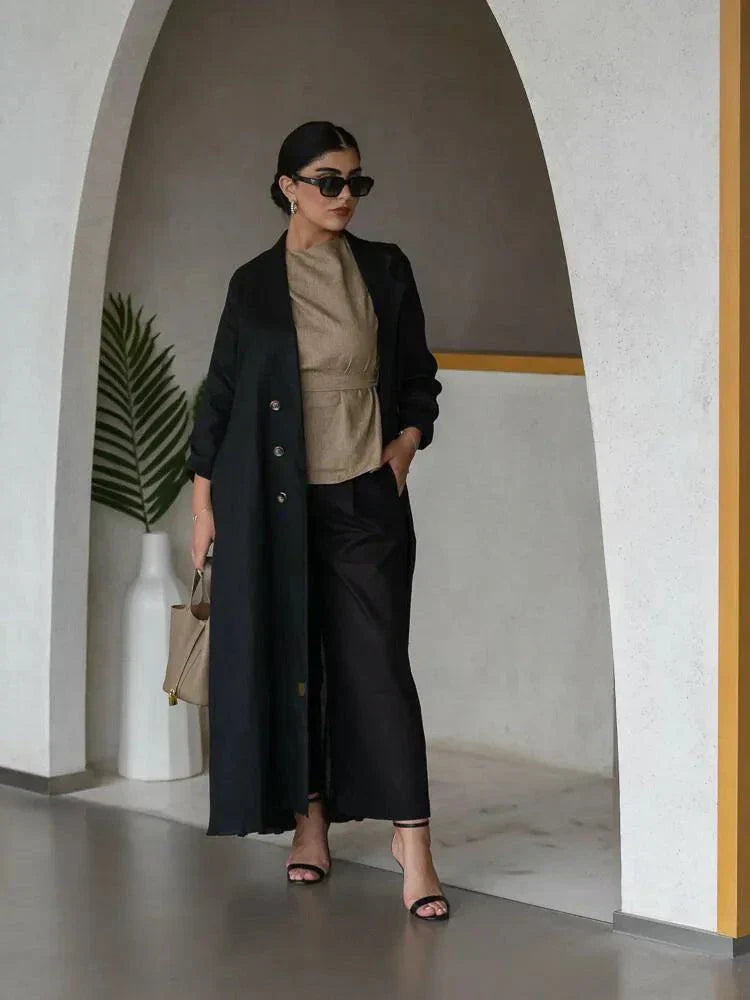 woman wearing elegant black linen abaya with structured collar and decorative buttons walking indoors