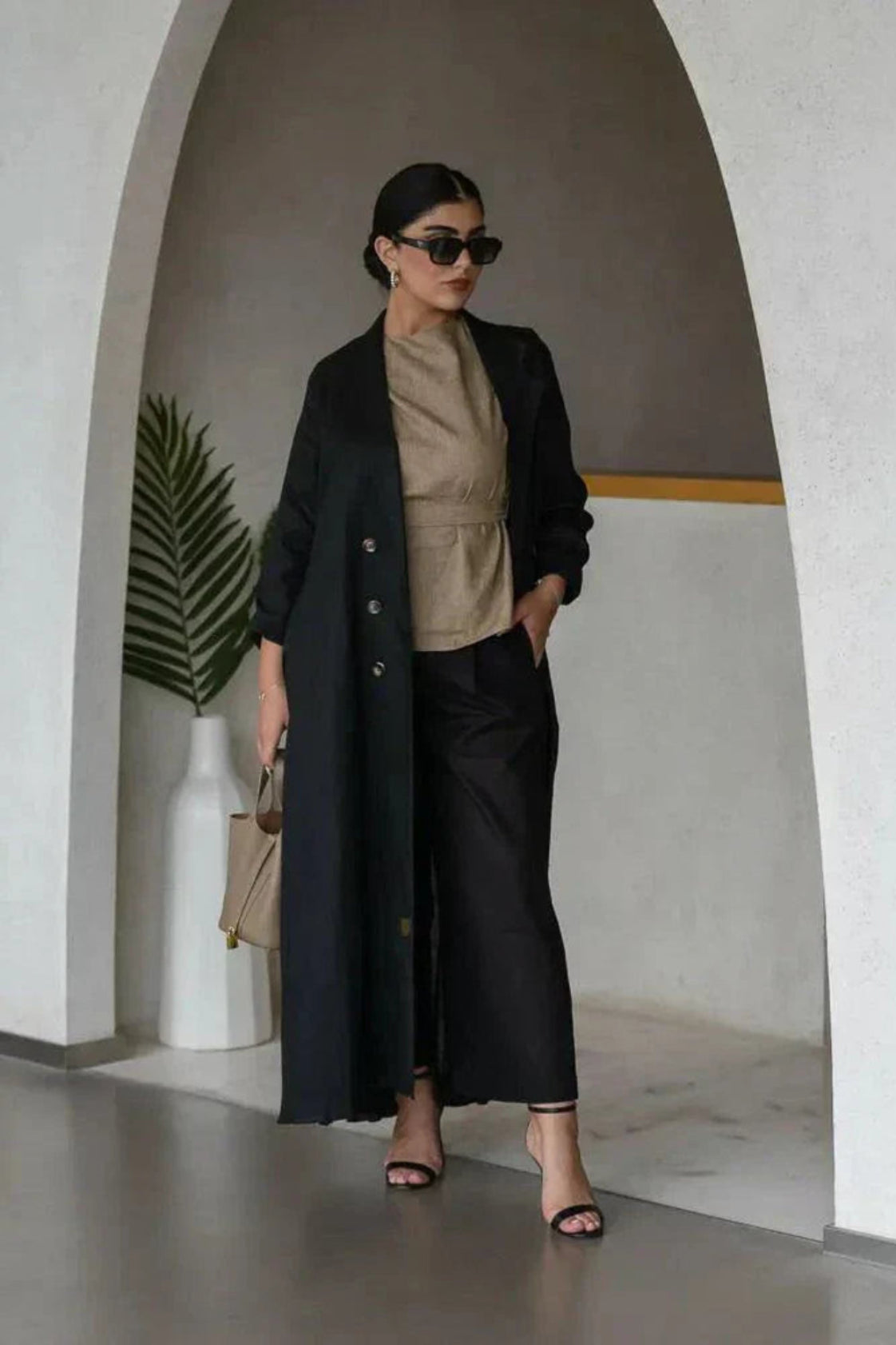 woman wearing elegant black linen abaya with structured collar and decorative buttons walking indoors