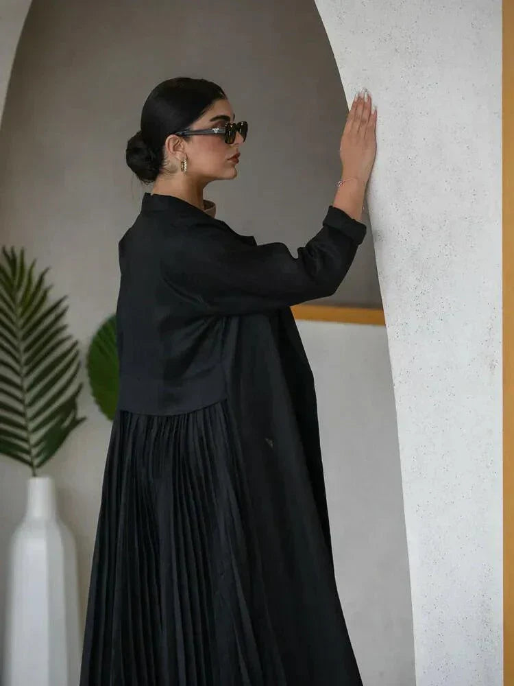 woman wearing elegant black linen abaya with structured collar and decorative buttons walking indoors