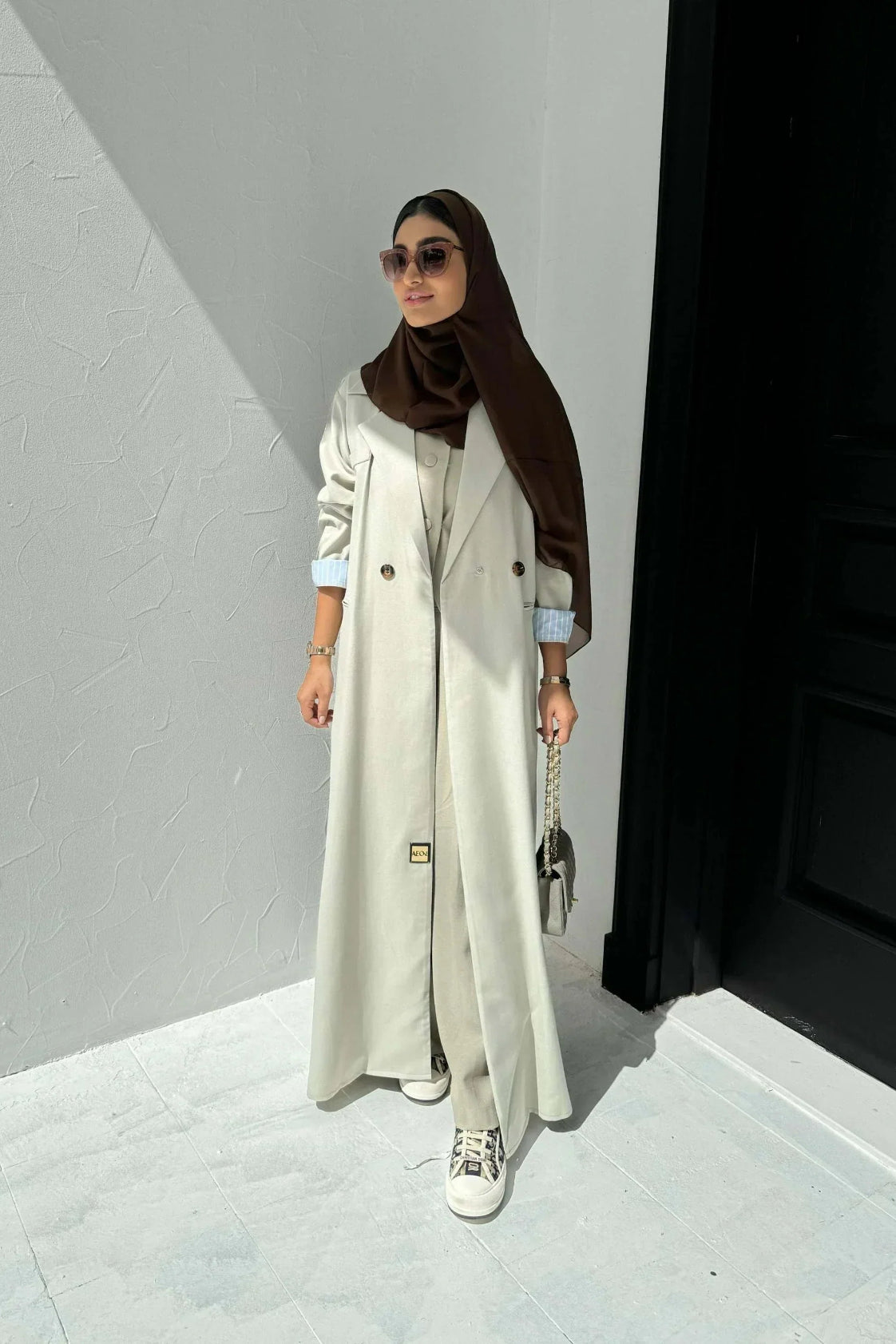 light beige linen blazer-style abaya with double-breasted front, structured shoulders, notched lapels, and contrast striped inner cuffs for sophisticated daily wear