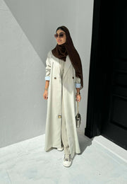 light beige linen blazer-style abaya with double-breasted front, structured shoulders, notched lapels, and contrast striped inner cuffs for sophisticated daily wear