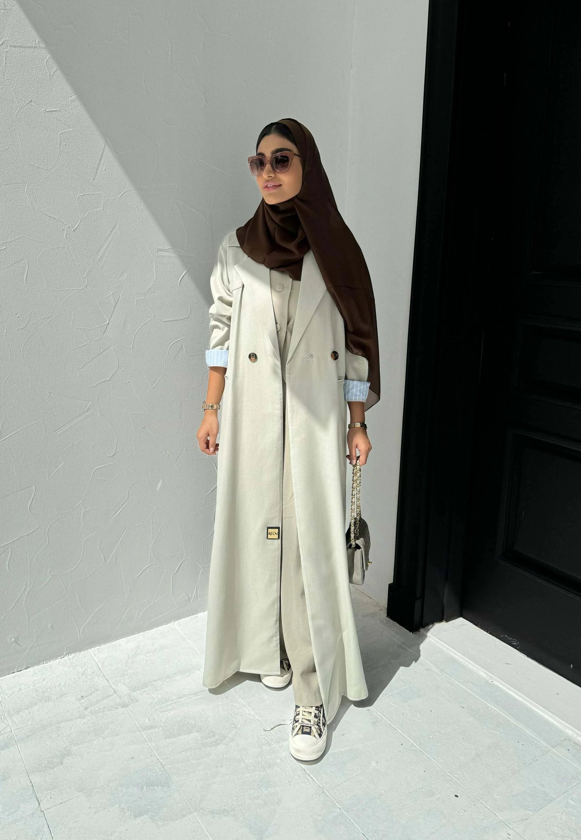 light beige linen blazer-style abaya with double-breasted front, structured shoulders, notched lapels, and contrast striped inner cuffs for sophisticated daily wear
