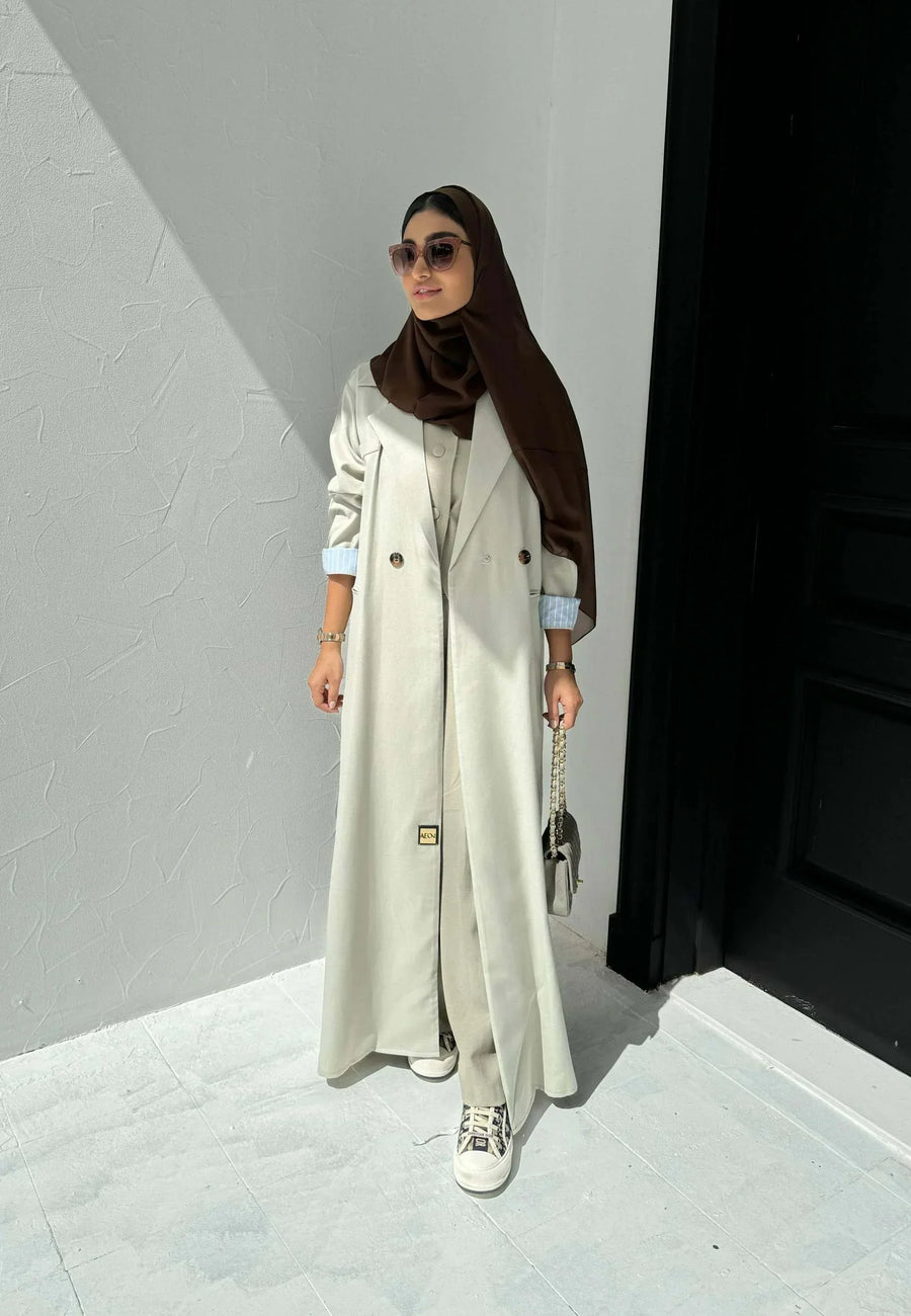 light beige linen blazer-style abaya with double-breasted front, structured shoulders, notched lapels, and contrast striped inner cuffs for sophisticated daily wear