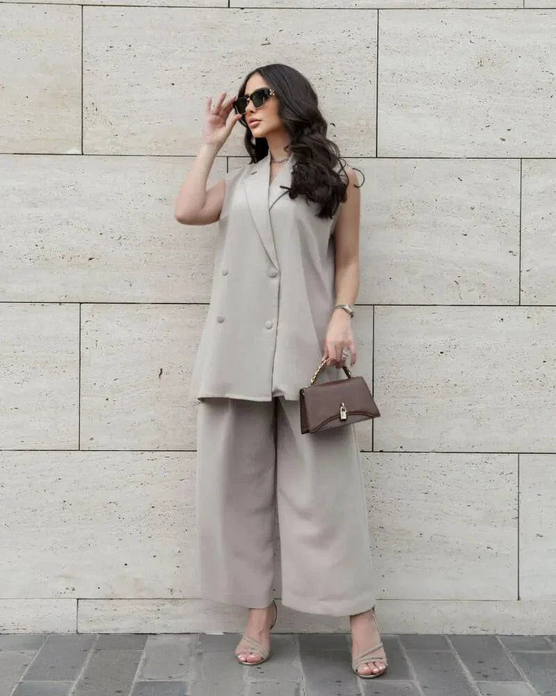Woman wearing a beige crepe sleeveless double-breasted vest with wide-leg pants and sunglasses.