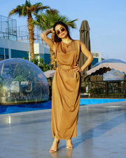 Woman wearing a camel-toned Camella crepe silk dress with a modest silhouette and long sleeves by a poolside
