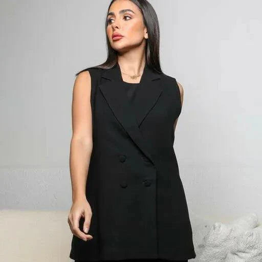 Woman wearing sleeveless black crepe double-breasted vest with sharp lapel collar styled with black wide-leg trousers in modern room - black crepe vest
